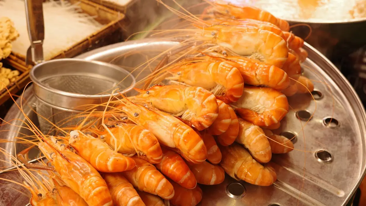Langoustines à la vapeur dans un cuit-vapeur, carapace rosée et chair opaque, gros plan culinaire.